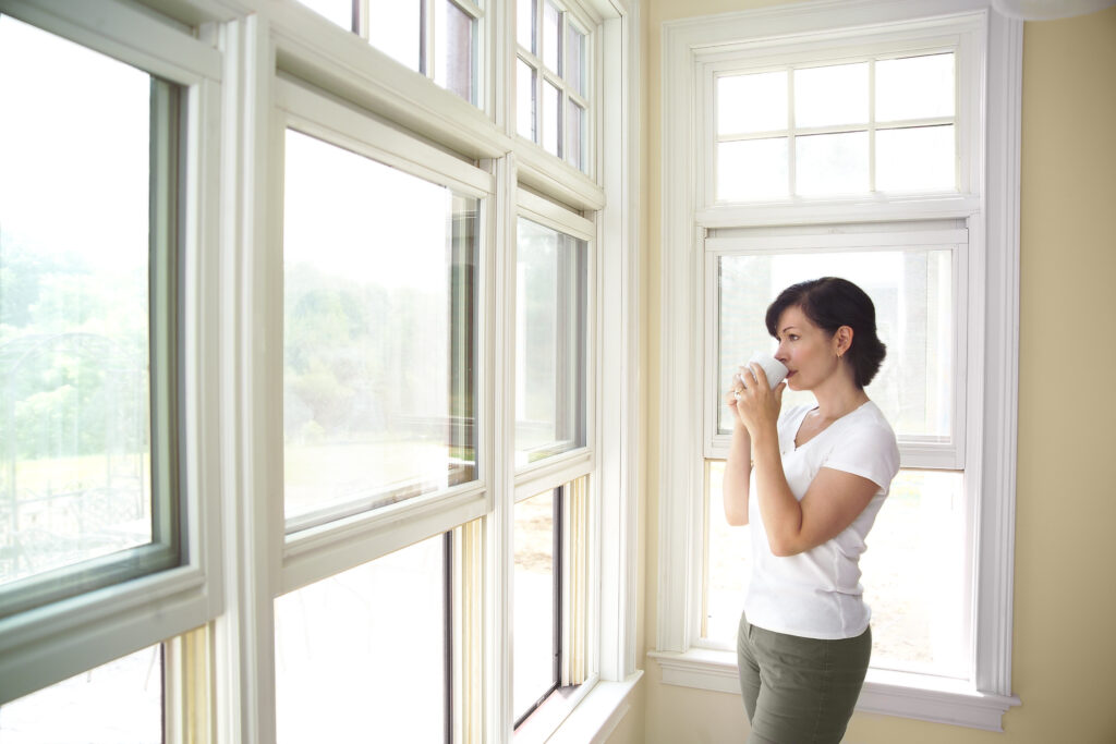 window standing in front of her new window replacements 